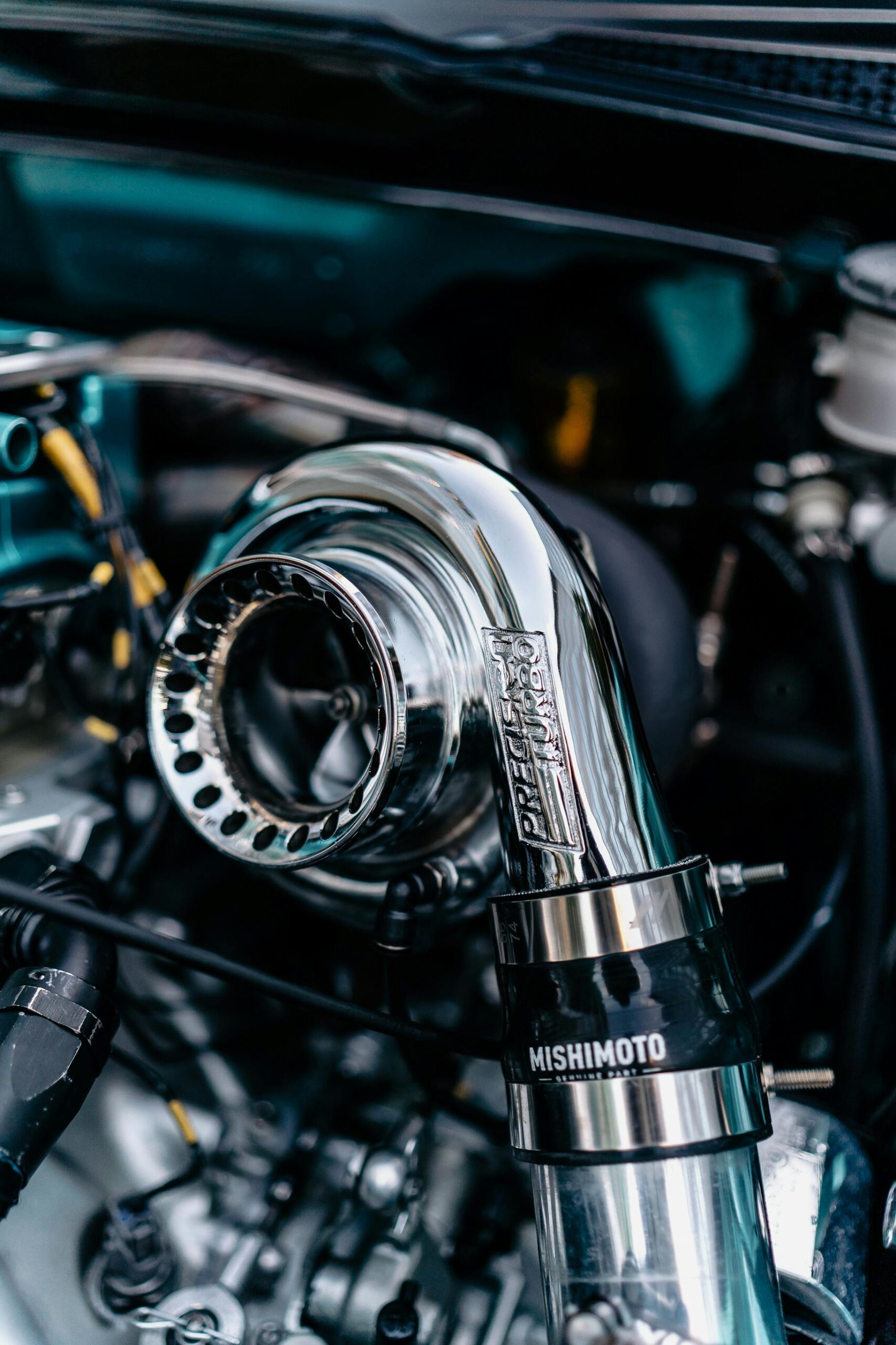 Detailed shot of a chrome turbocharger in a car engine bay, reflecting light.