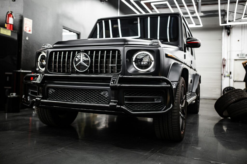 A striking black Mercedes-Benz G-Class SUV, a symbol of luxury, parked in a modern garage setting.